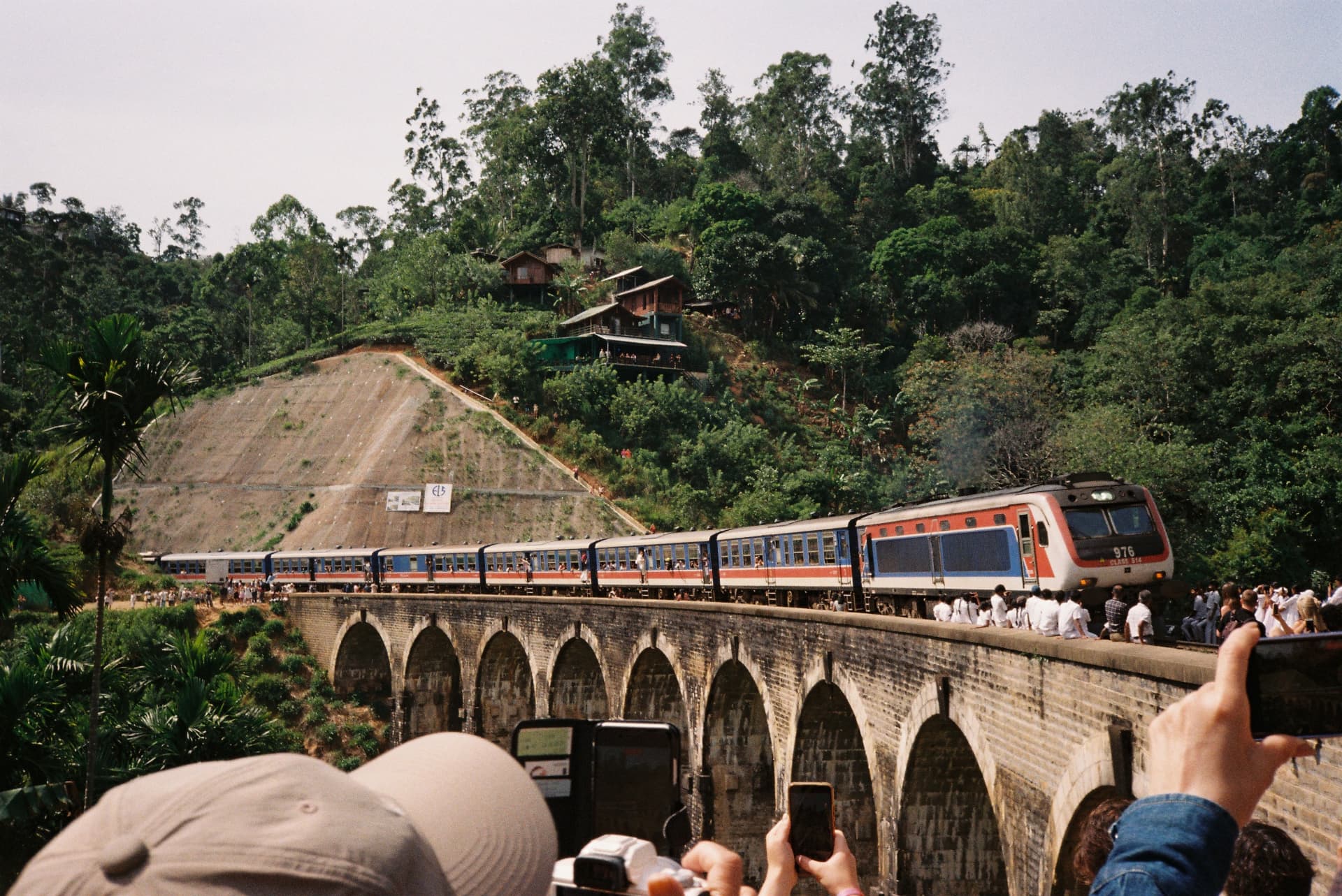 Blue train crossing the Nine Arch Bridge above the jungle