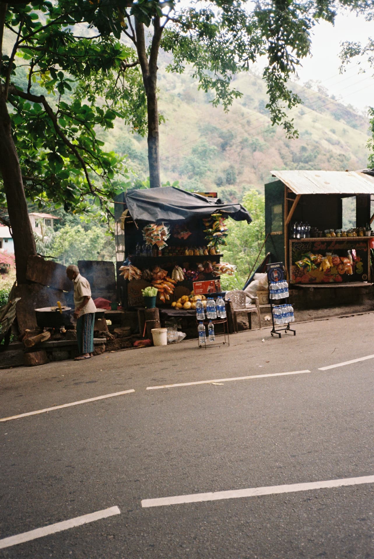 Roadside stall with fruit, snacks and water bottles by a mountain road