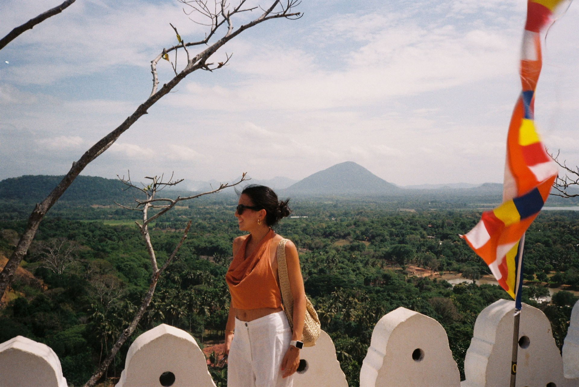 Woman on a temple terrace with Buddhist prayer flags and a mountain behind