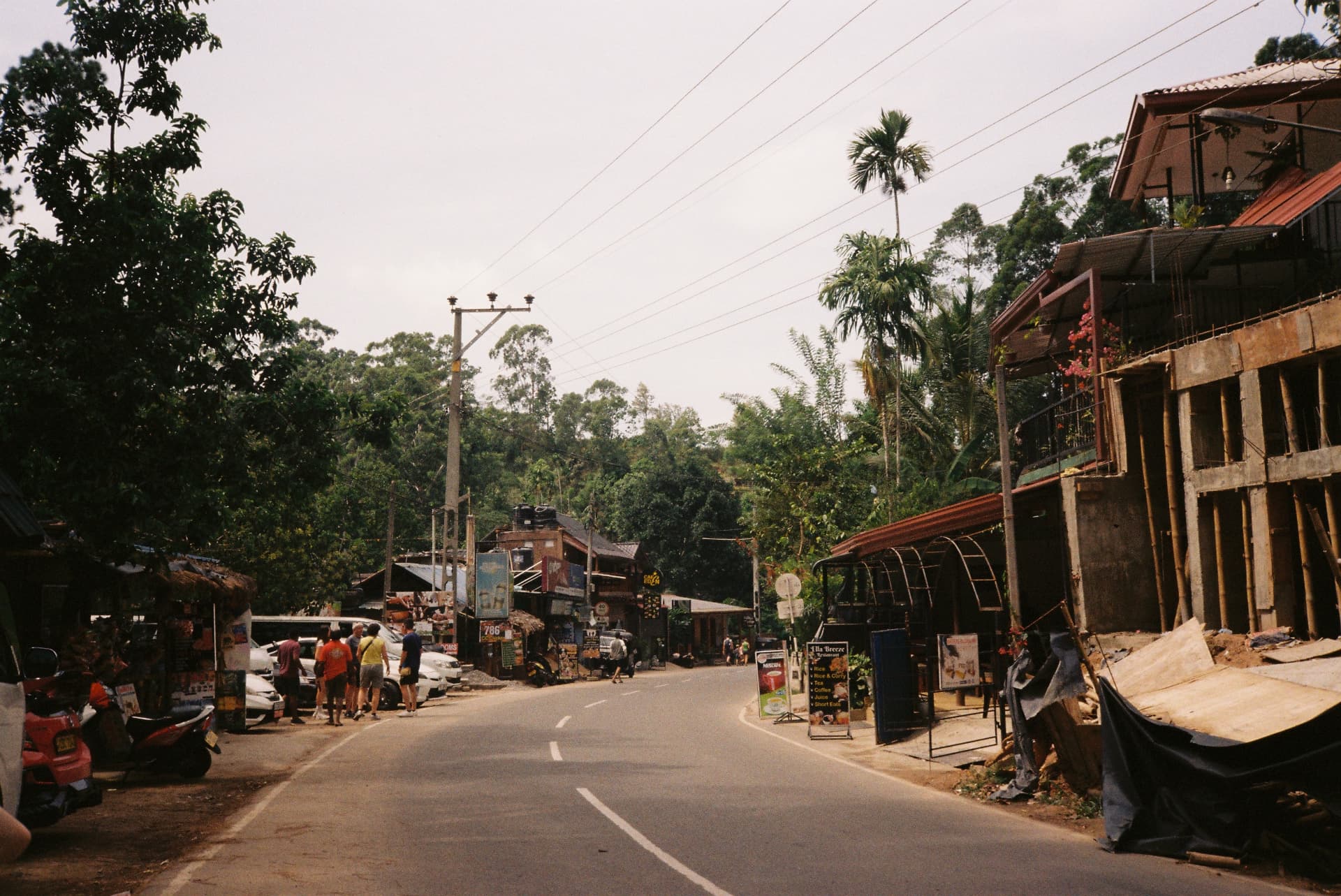 Main street of Ella with shops, tuk-tuks and palm trees
