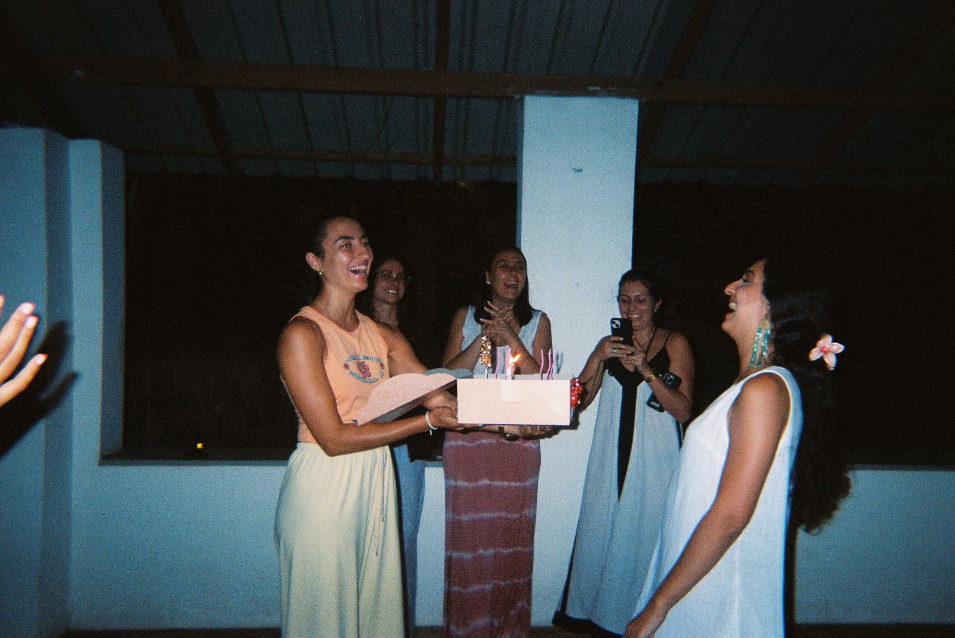 A group of friends celebrating with a cake and candles at night
