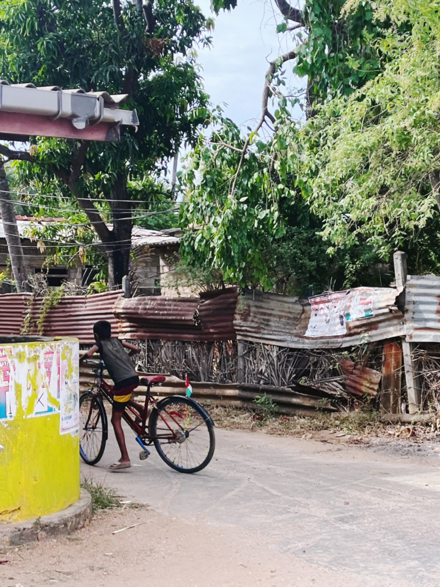 Boy with a red bicycle beside a yellow wall on a village street