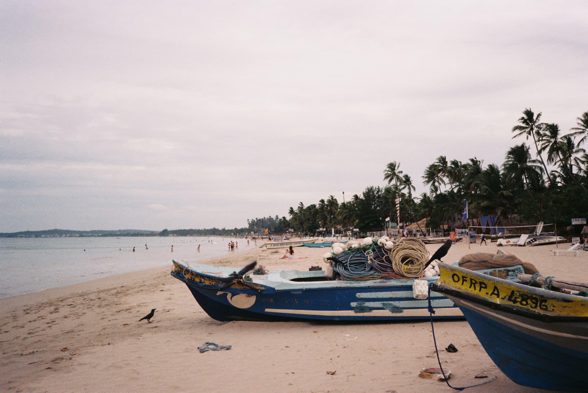 Blue fishing boats loaded with ropes and floats on the sand